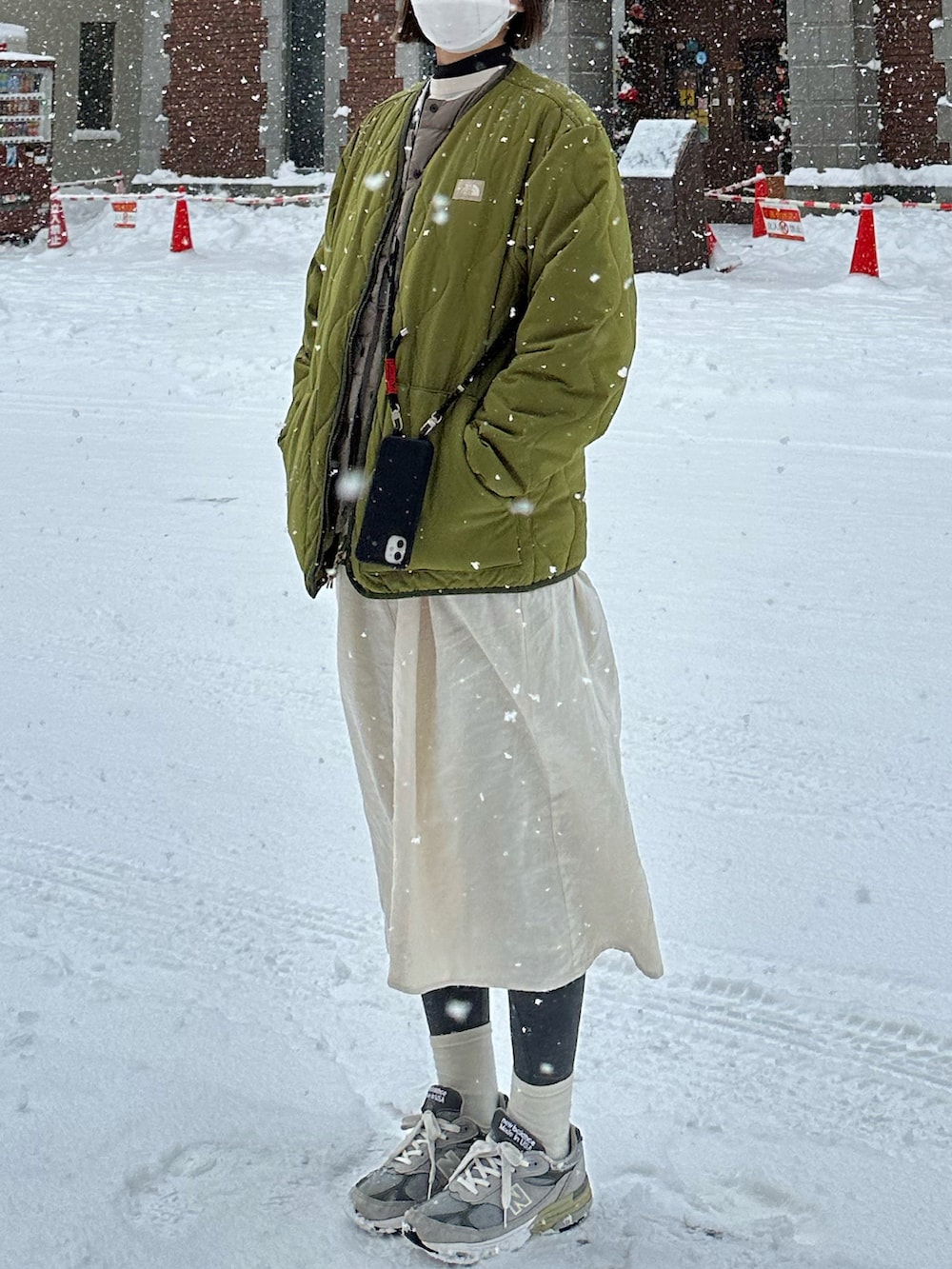 ホワイト系のシャツワンピース、グリーン系のダウンジャケット/コート、ベージュ系のダウンベストを着用したレディースの冬コーディネートの2枚目の写真