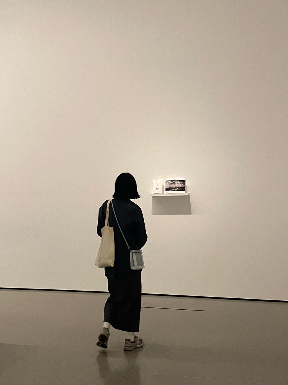 シルバー系のスニーカー、グレー系のスカート、ブルー系のショルダーバッグを着用したレディースの秋コーディネートの3枚目の写真