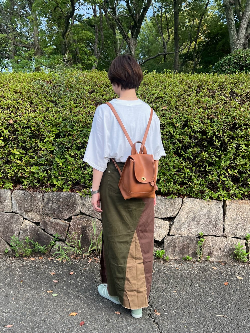 グリーン系のスニーカー、ホワイト系のTシャツ/カットソー、ブラウン系のスカートを着用したレディースの秋コーディネートの2枚目の写真