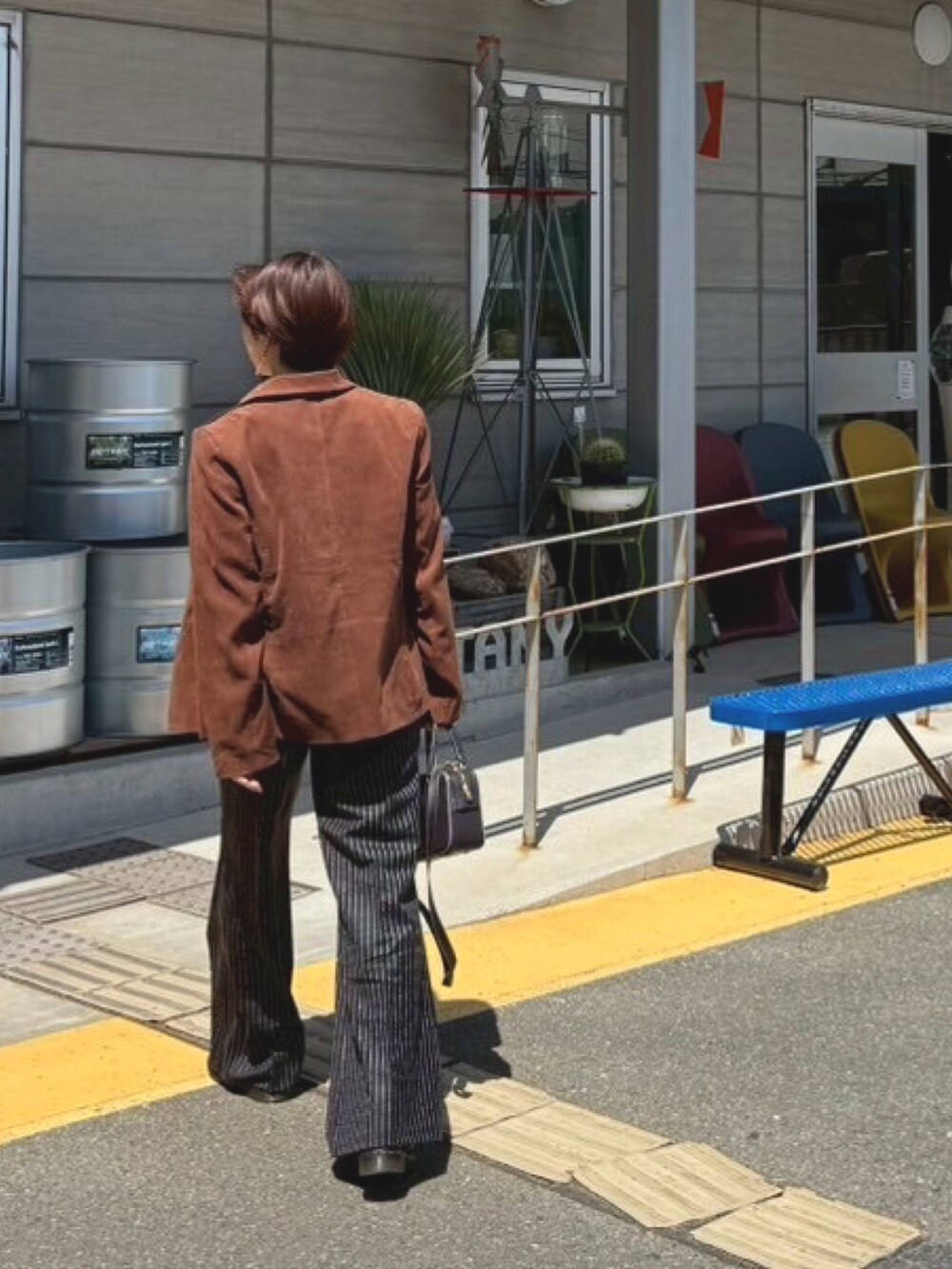 ブラウン系のテーラードジャケット、ブラック系のその他シューズ、ブラック系のスラックスを着用したレディースの春コーディネートの2枚目の写真