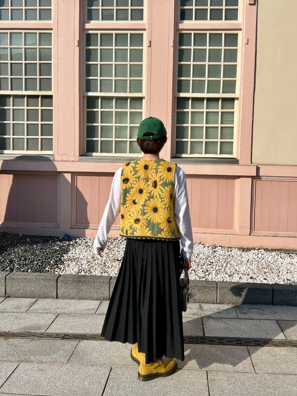 イエロー系のブーツ、イエロー系のベスト、ブラック系のスカートを着用したレディースの春コーディネートの2枚目の写真