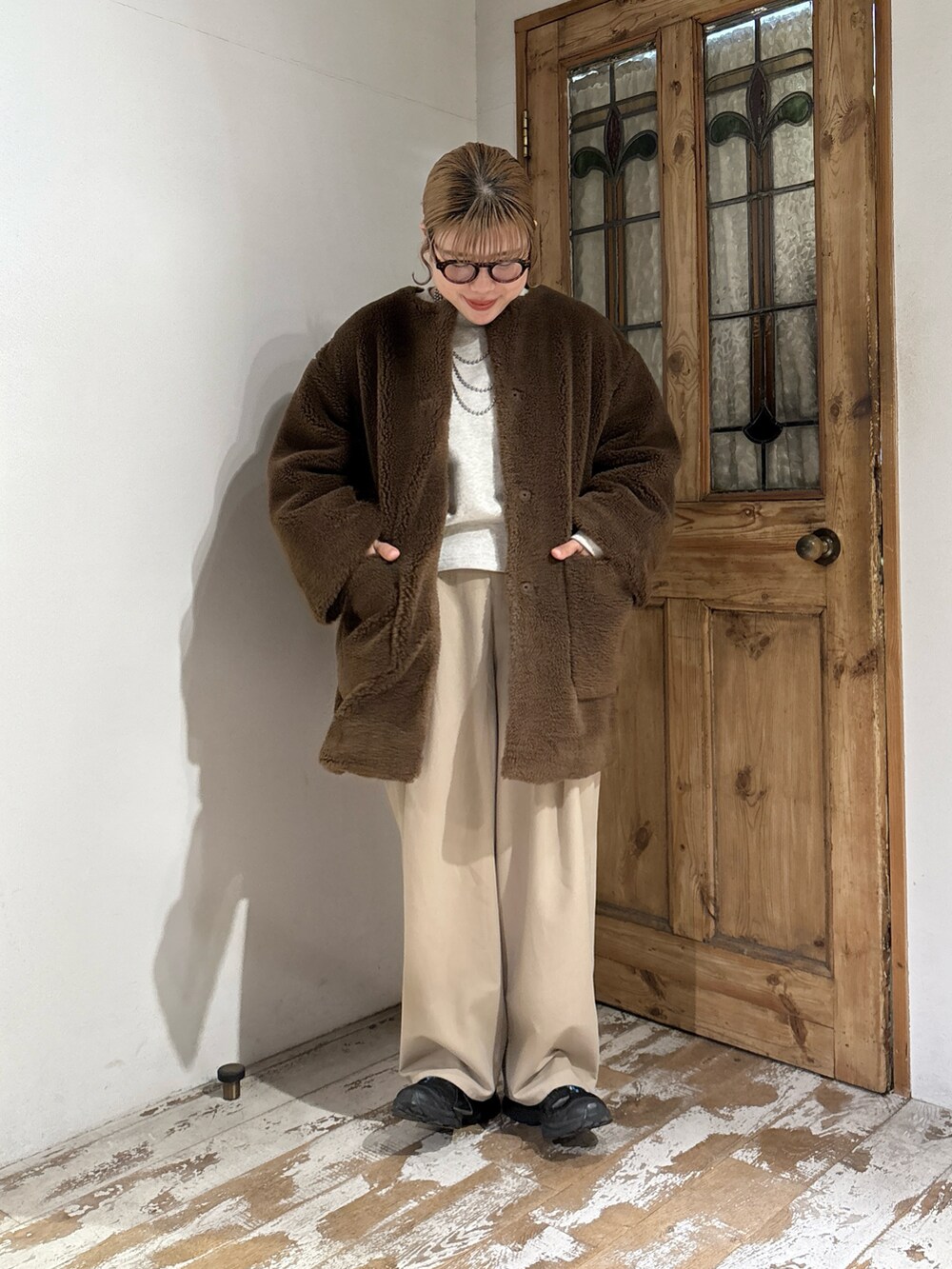 ブラウン系のノーカラーコート、ベージュ系のスウェット、ベージュ系のスラックスを着用したレディースの秋コーディネートの3枚目の写真