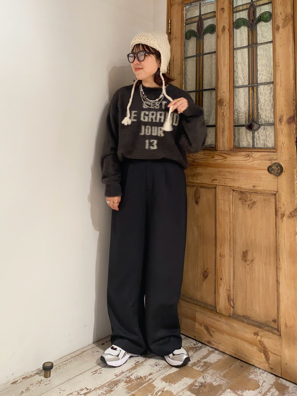 ブラウン系のニット/セーター、ブラック系のスラックス、ホワイト系のスニーカーを着用したレディースの冬コーディネートの2枚目の写真