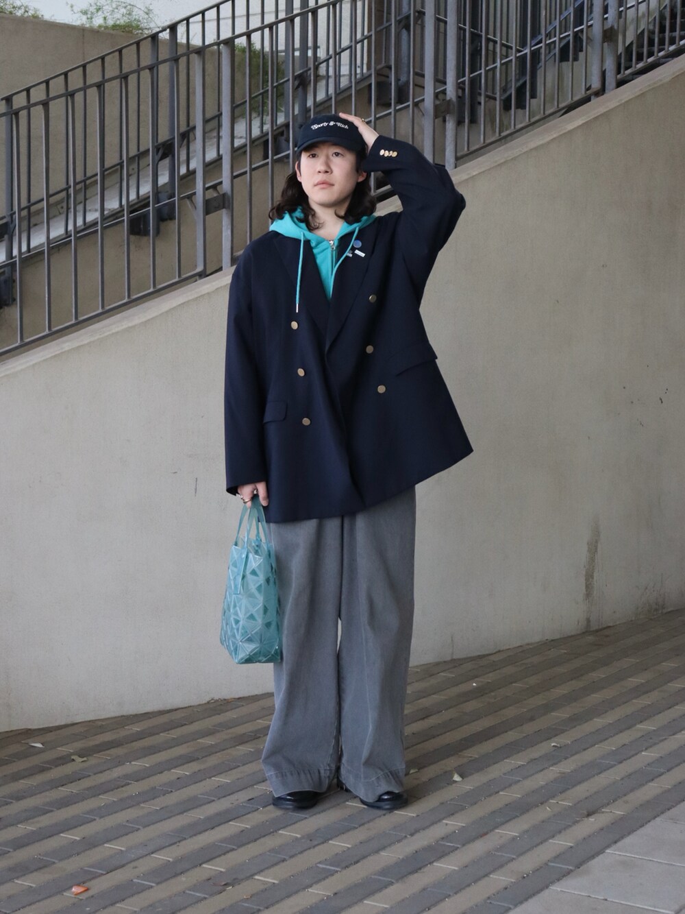 グリーン系のトートバッグ、ブルー系のテーラードジャケット、ブルー系のパーカーを着用したメンズの春コーディネートの5枚目の写真