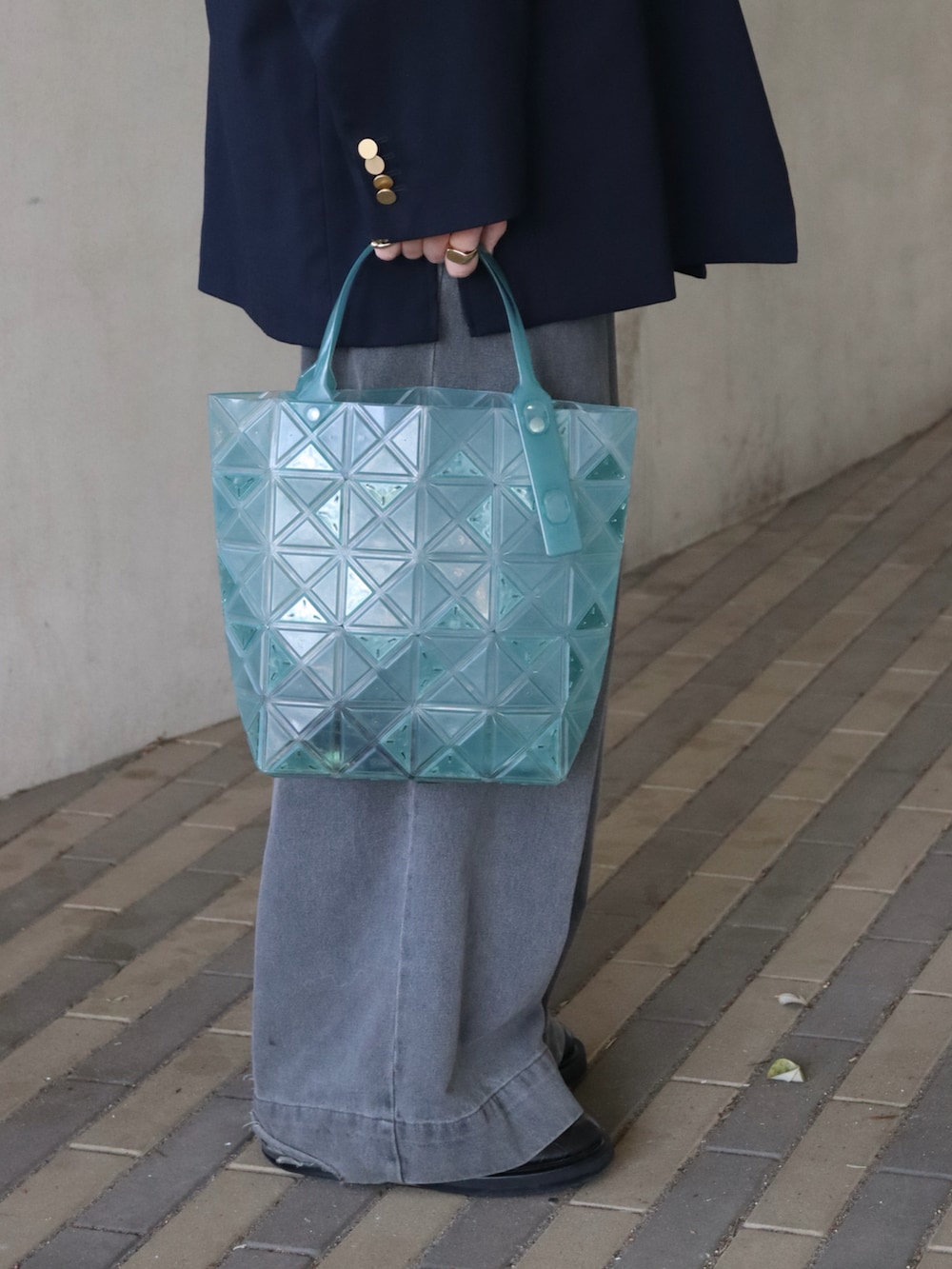 グリーン系のトートバッグ、ブルー系のテーラードジャケット、ブルー系のパーカーを着用したメンズの春コーディネートの2枚目の写真