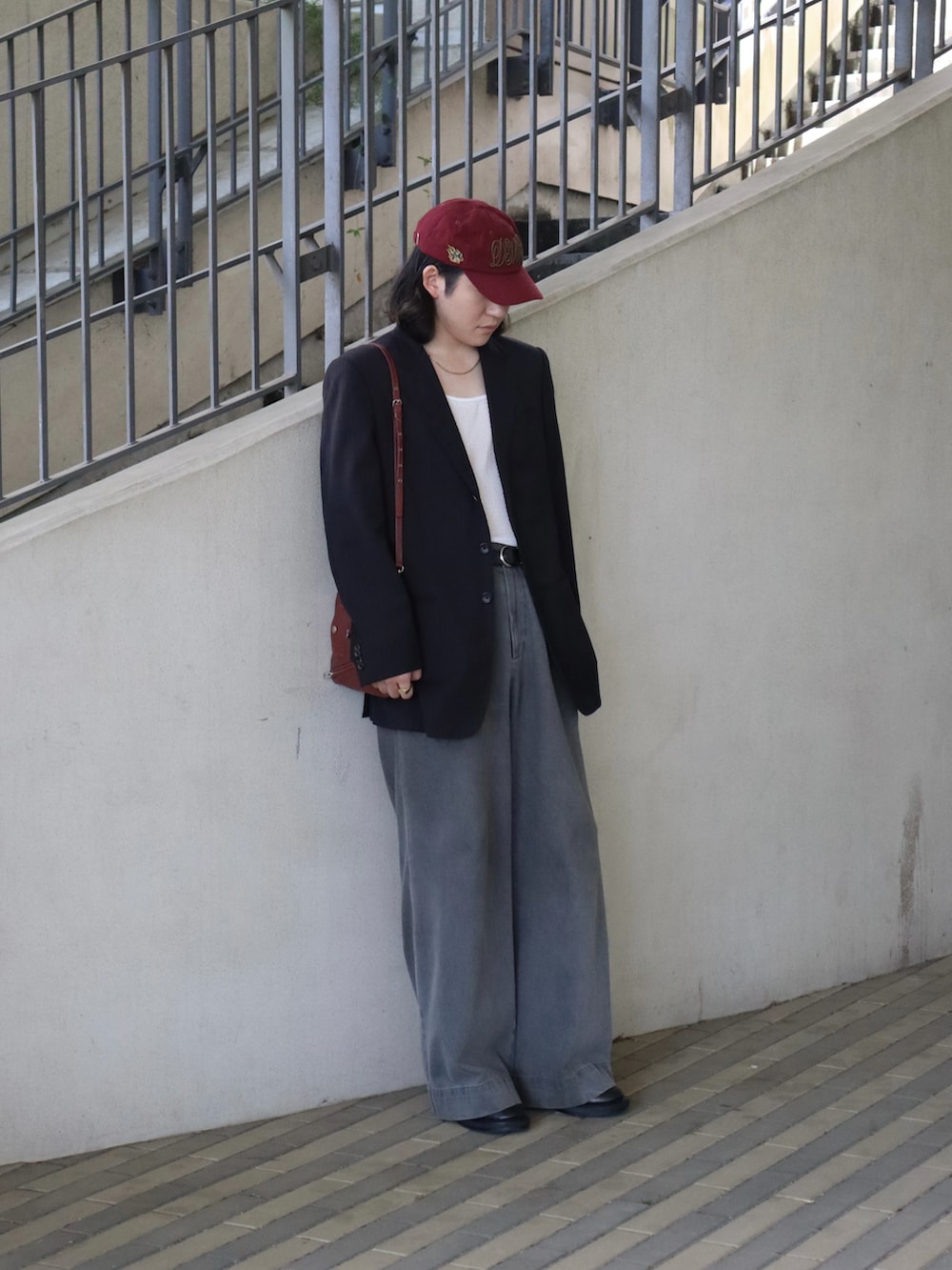 ホワイト系のタンクトップ、ブラック系のテーラードジャケット、レッド系のバッグを着用したメンズの春コーディネートの4枚目の写真