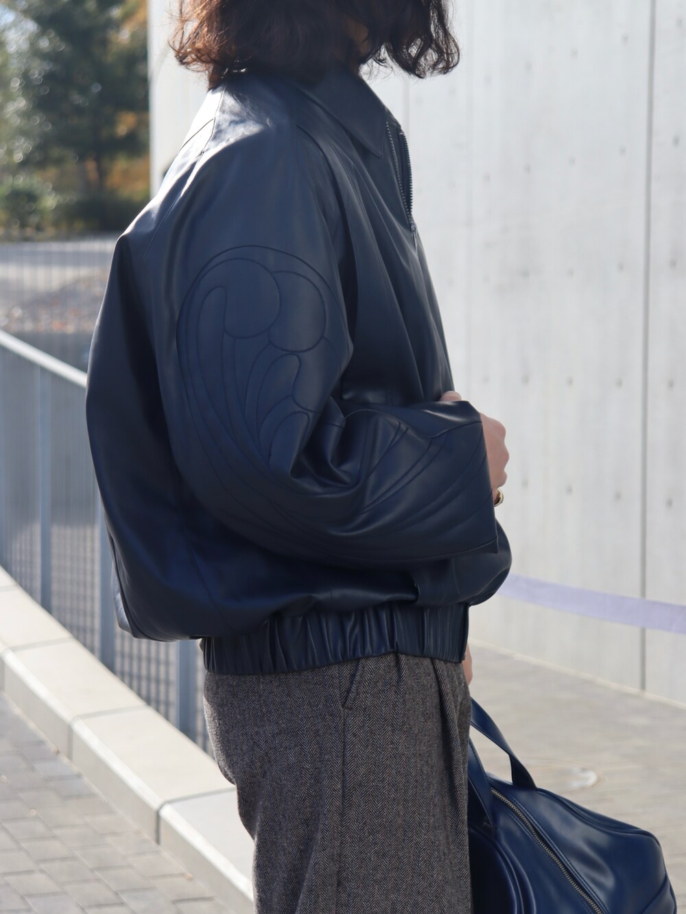 ブルー系のジャケット/アウター、グレー系のスラックス、ブルー系のボストンバッグを着用したメンズの冬コーディネートの4枚目の写真