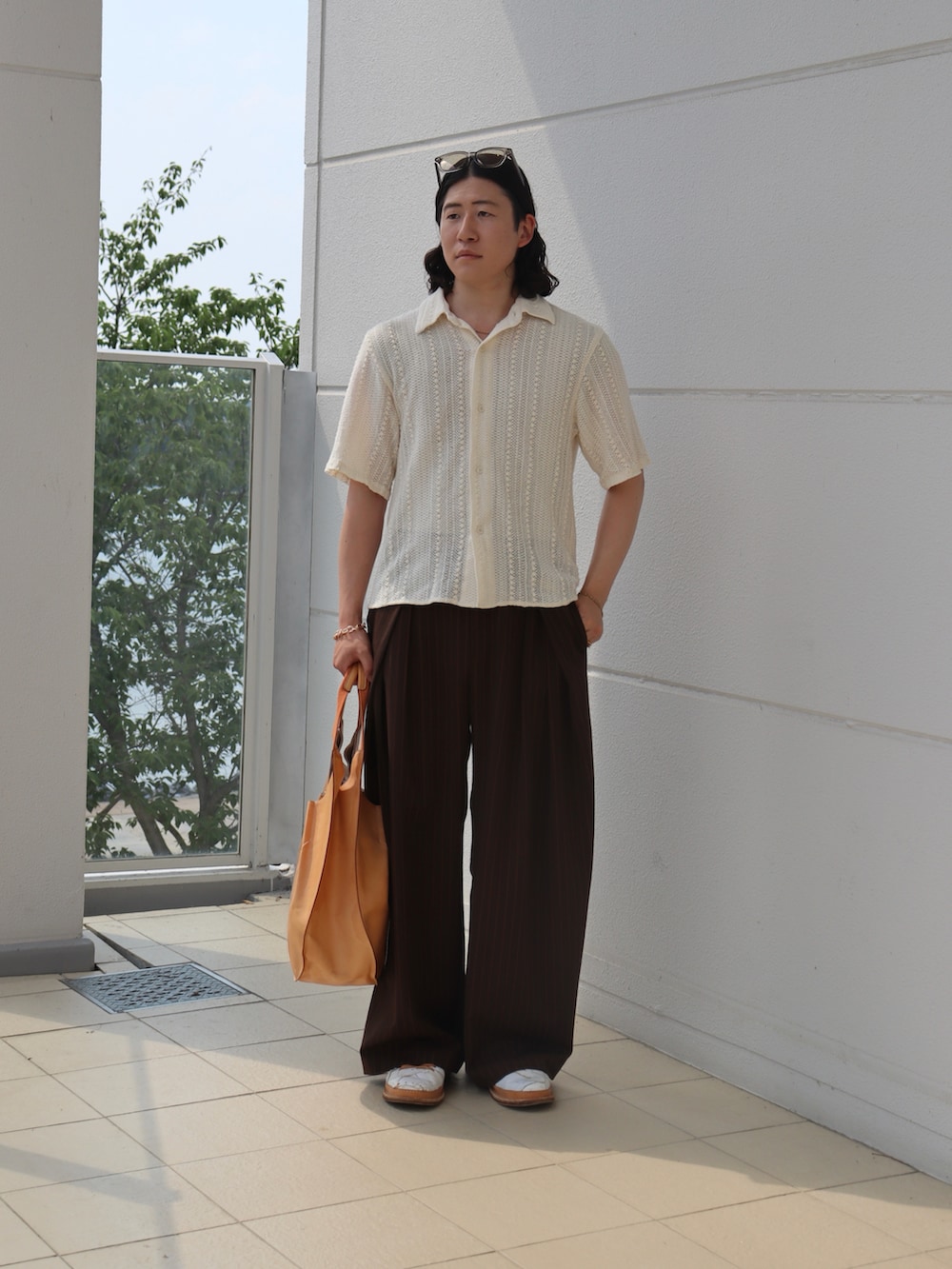 ホワイト系のシャツ/ブラウス、ブラウン系のスラックス、オレンジ系のトートバッグを着用したメンズの秋コーディネートの2枚目の写真