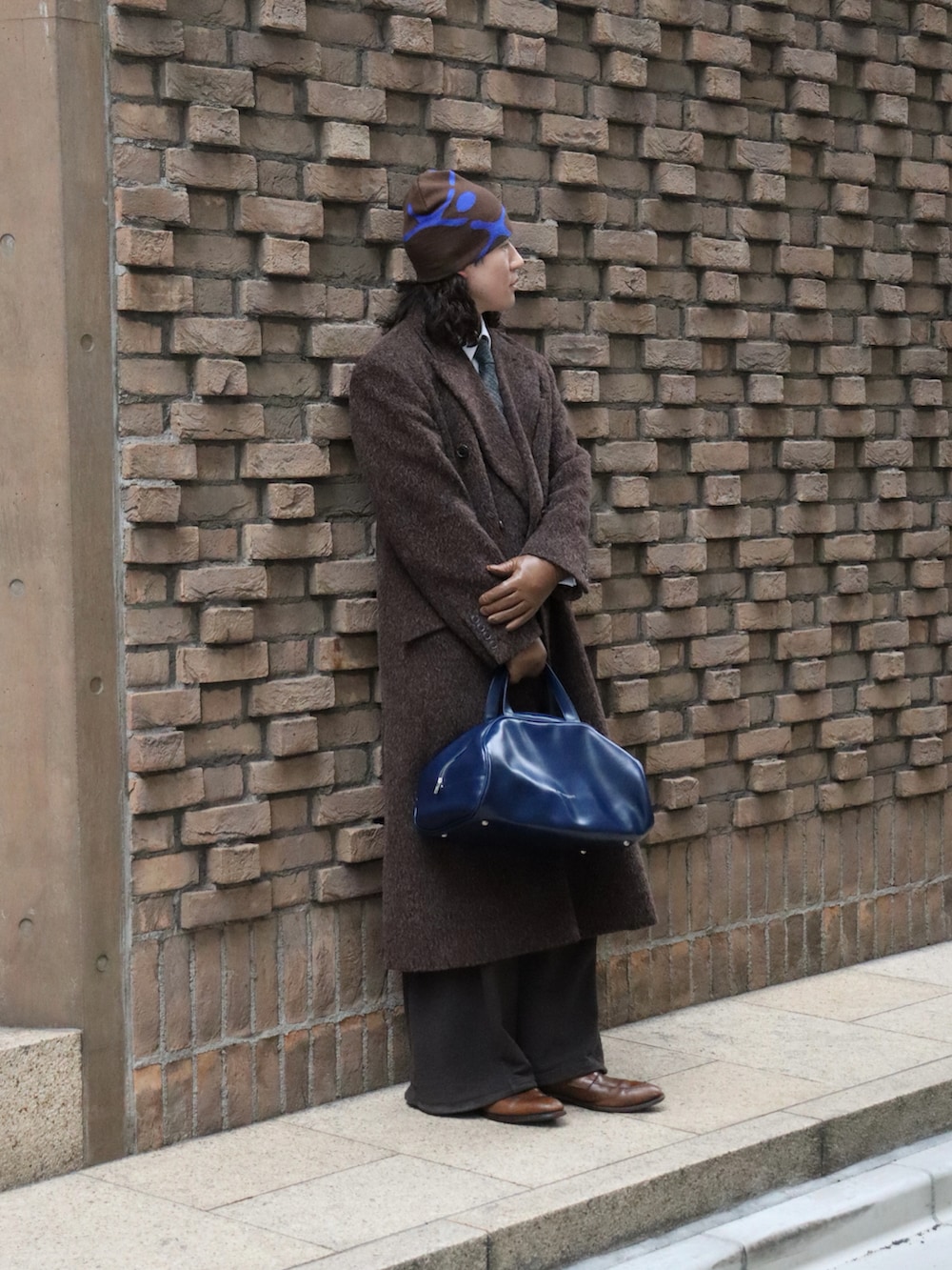 ブルー系のボストンバッグ、ブラウン系のスウェットパンツ、ブラウン系のローファーを着用したメンズの冬コーディネートの3枚目の写真