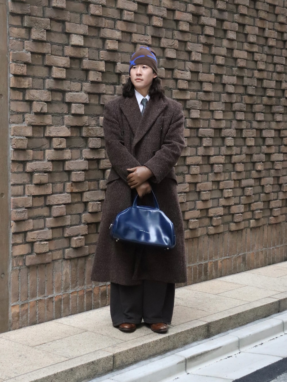 ブルー系のボストンバッグ、ブラウン系のスウェットパンツ、ブラウン系のローファーを着用したメンズの冬コーディネートの2枚目の写真