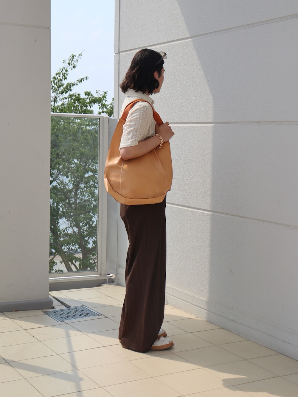 ホワイト系のシャツ/ブラウス、ブラウン系のスラックス、オレンジ系のトートバッグを着用したメンズの秋コーディネートの4枚目の写真