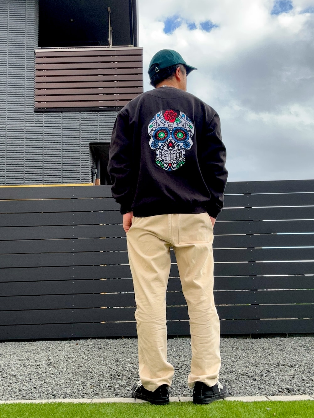 ブラック系のスニーカー、ベージュ系のチノパンツ、グリーン系のキャップを着用したメンズの秋コーディネートの2枚目の写真