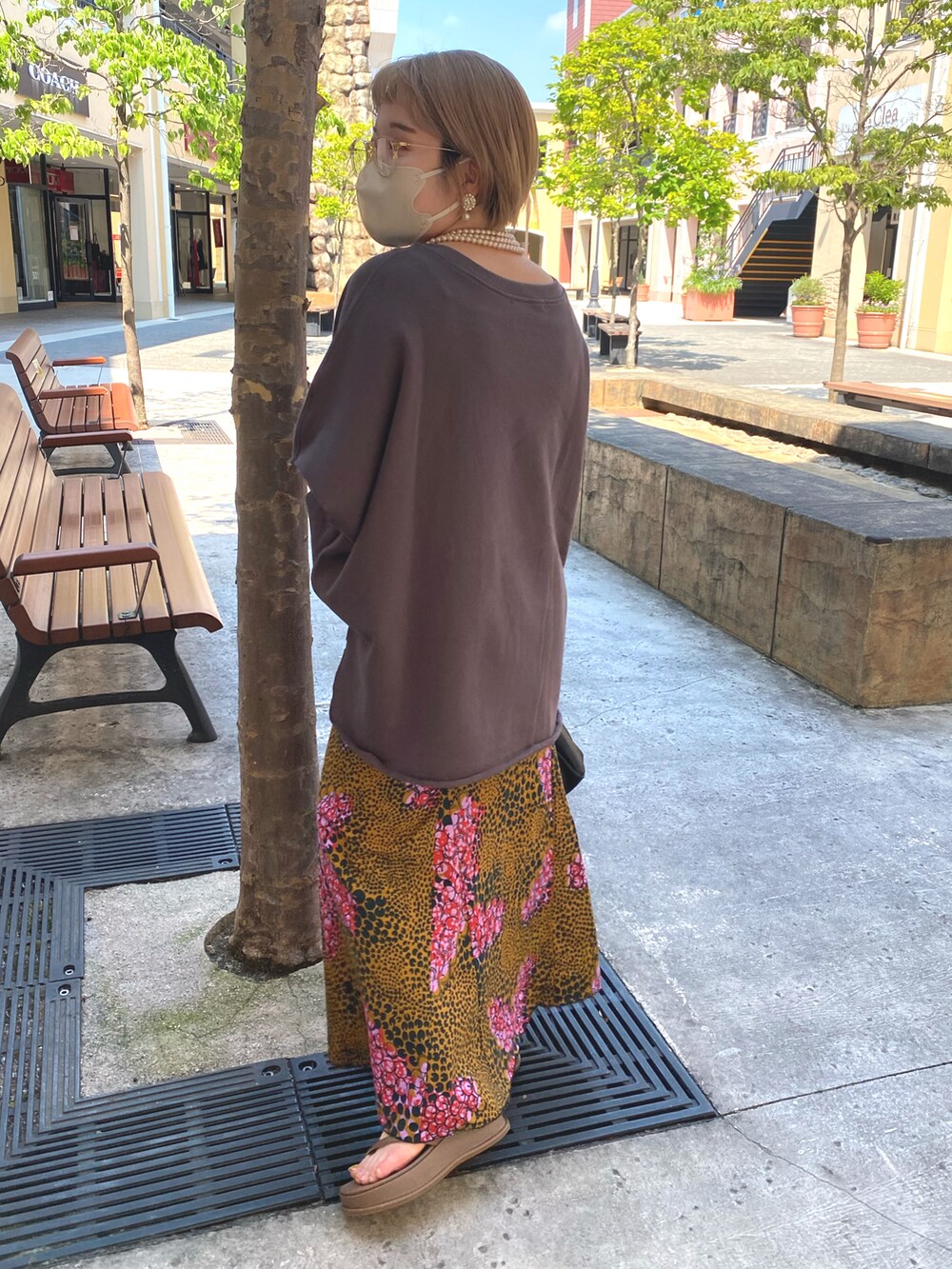 グレー系のスウェット、ピンク系のスカート、ブラック系のハンドバッグを着用したレディースの夏コーディネートの2枚目の写真