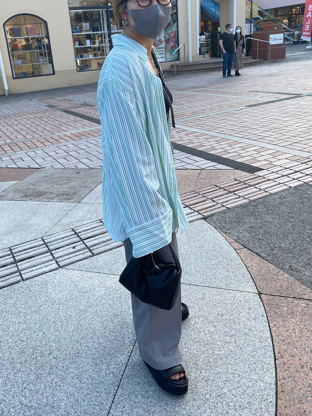 グレー系のスラックス、グリーン系のシャツ/ブラウス、ブラック系のハンドバッグを着用したレディースの夏コーディネートの2枚目の写真