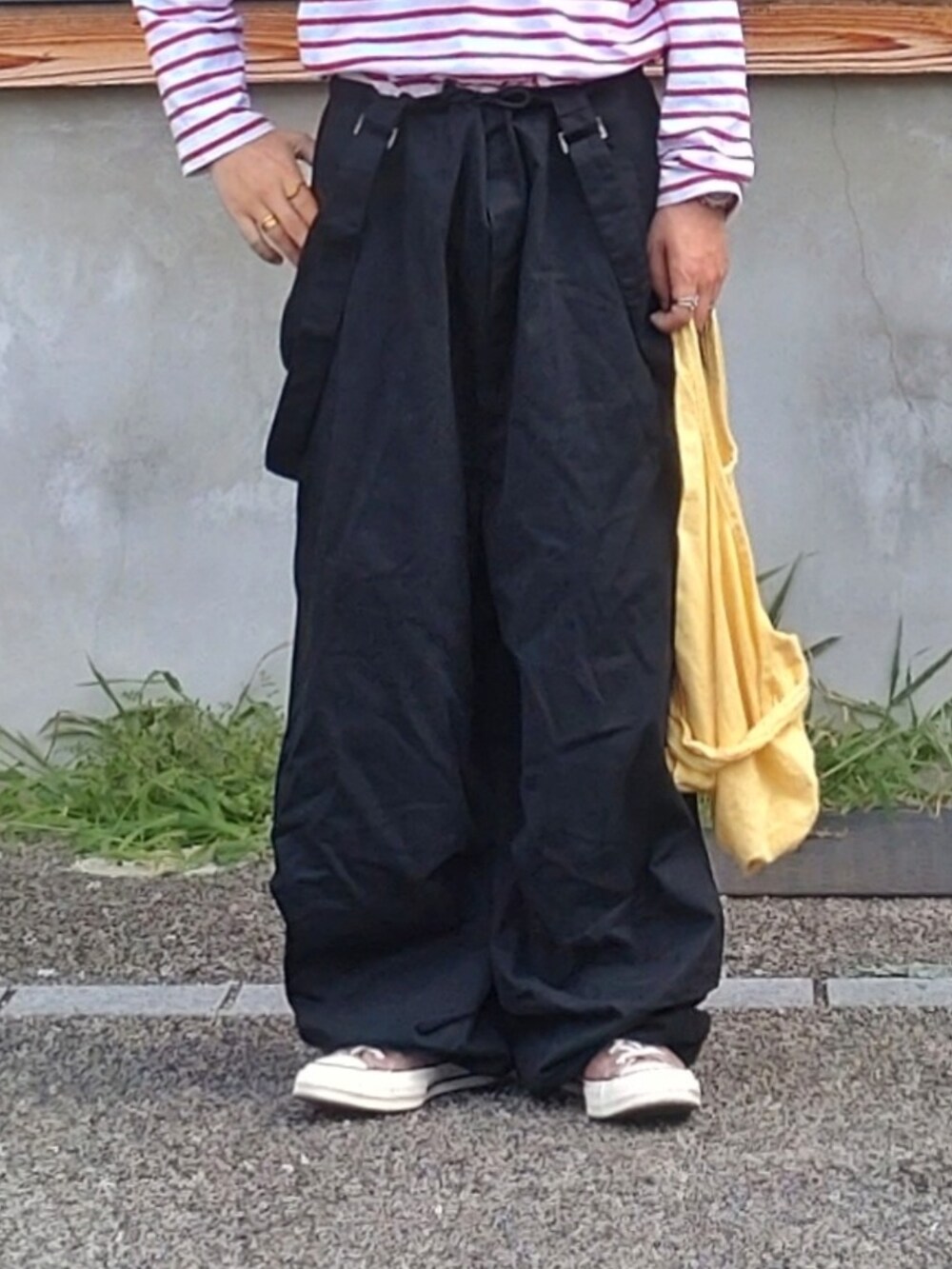 ブラック系のサロペット/オーバーオール、イエロー系のエコバッグ/サブバッグ、オレンジ系のカーディガン/ボレロを着用したメンズの秋コーディネートの2枚目の写真