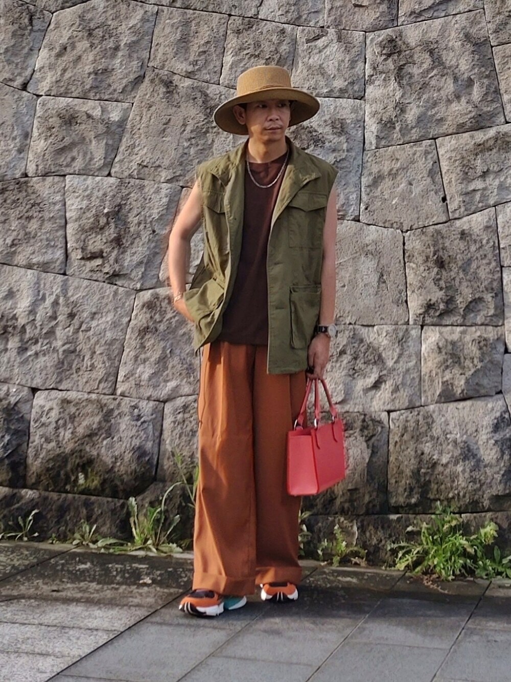 ブラウン系のTシャツ/カットソー、グリーン系のベスト、オレンジ系のスラックスを着用したメンズの夏コーディネートの2枚目の写真