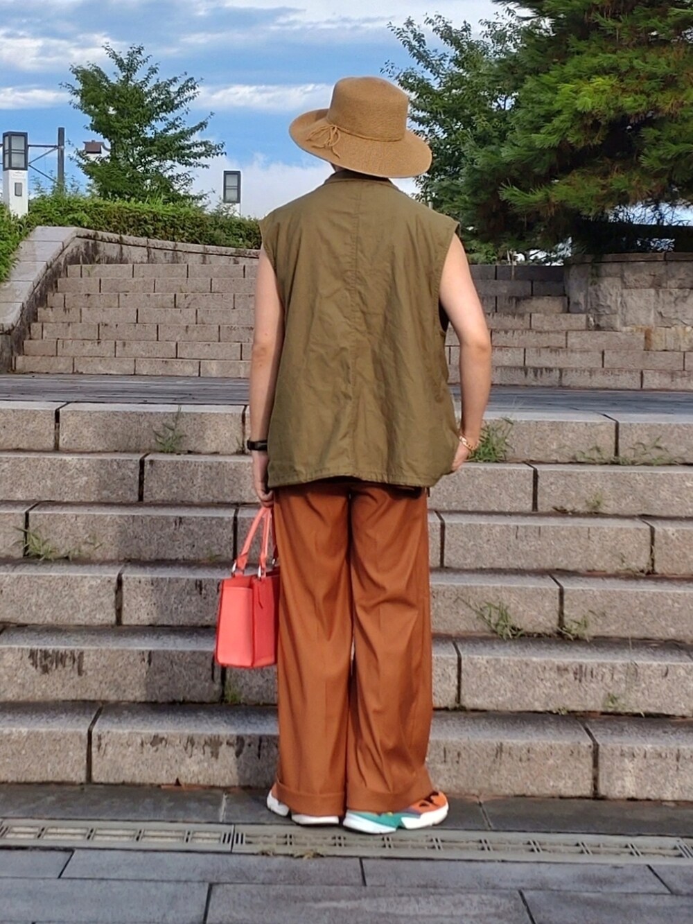 ブラウン系のTシャツ/カットソー、グリーン系のベスト、オレンジ系のスラックスを着用したメンズの夏コーディネートの3枚目の写真