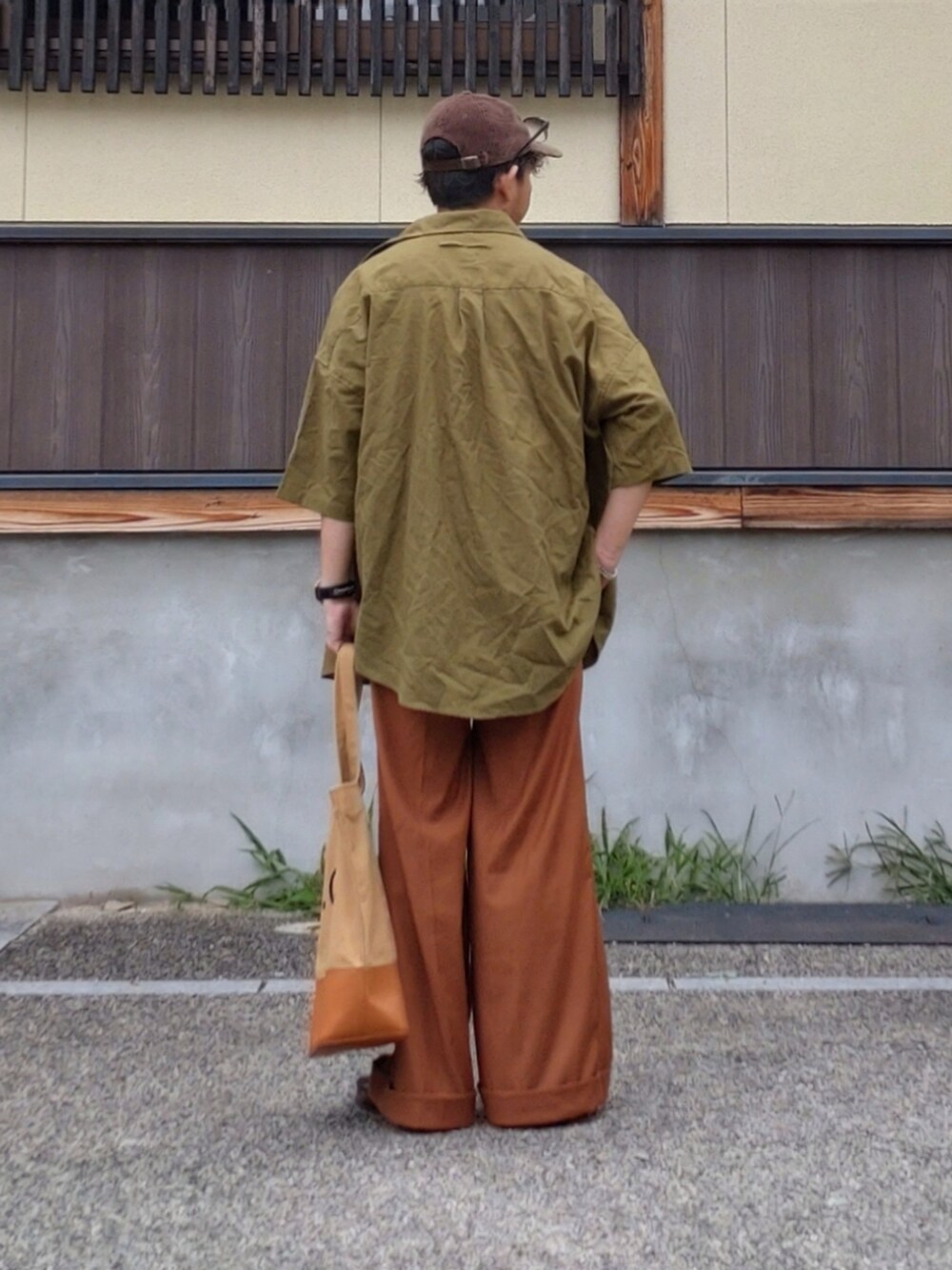 ホワイト系のTシャツ/カットソー、ブラウン系のトートバッグ、オレンジ系のスラックスを着用したメンズの夏コーディネートの3枚目の写真