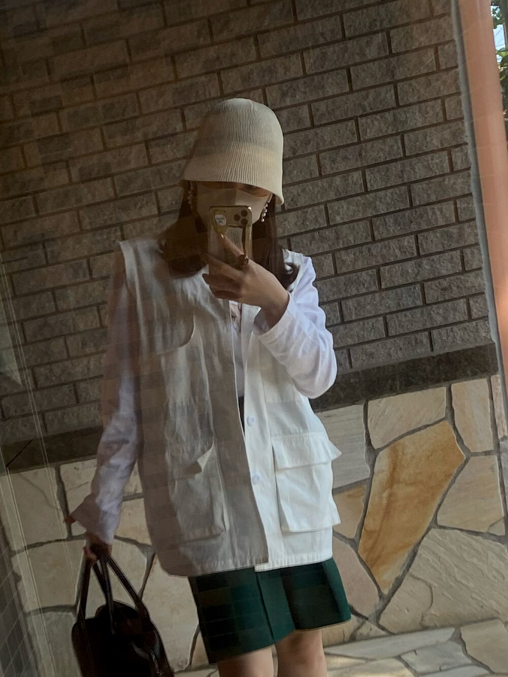 ホワイト系のベスト、ホワイト系のTシャツ/カットソー、ブラック系のブーツを着用したレディースの春コーディネートの2枚目の写真