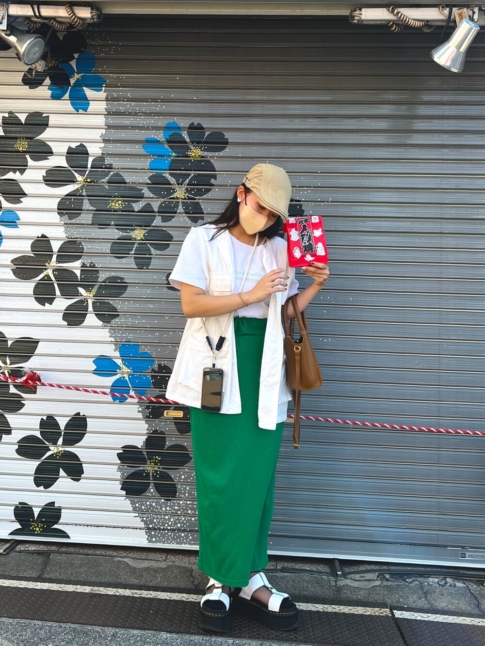 ホワイト系のベスト、グリーン系のスカート、ホワイト系のサンダルを着用したレディースの秋コーディネートの2枚目の写真