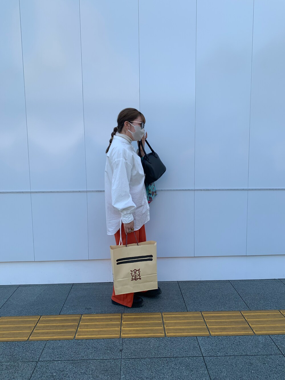 ホワイト系のシャツ/ブラウス、オレンジ系のパンツ、ブラック系のブーツを着用したレディースの春コーディネートの2枚目の写真