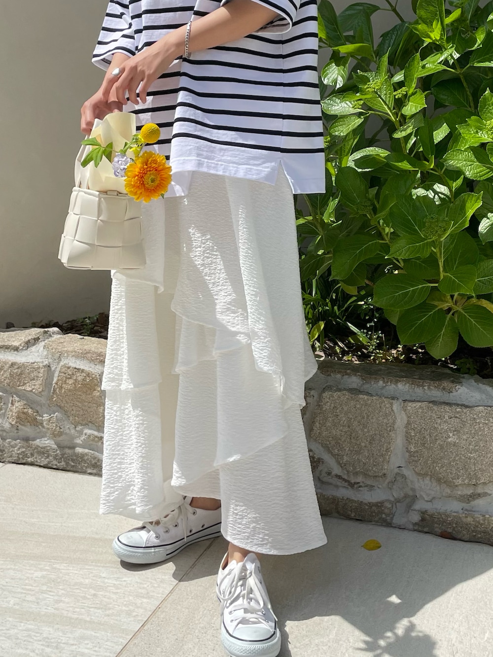 ホワイト系のTシャツ/カットソー、ホワイト系のスカート、ホワイト系のスニーカーを着用したレディースの春コーディネートの2枚目の写真