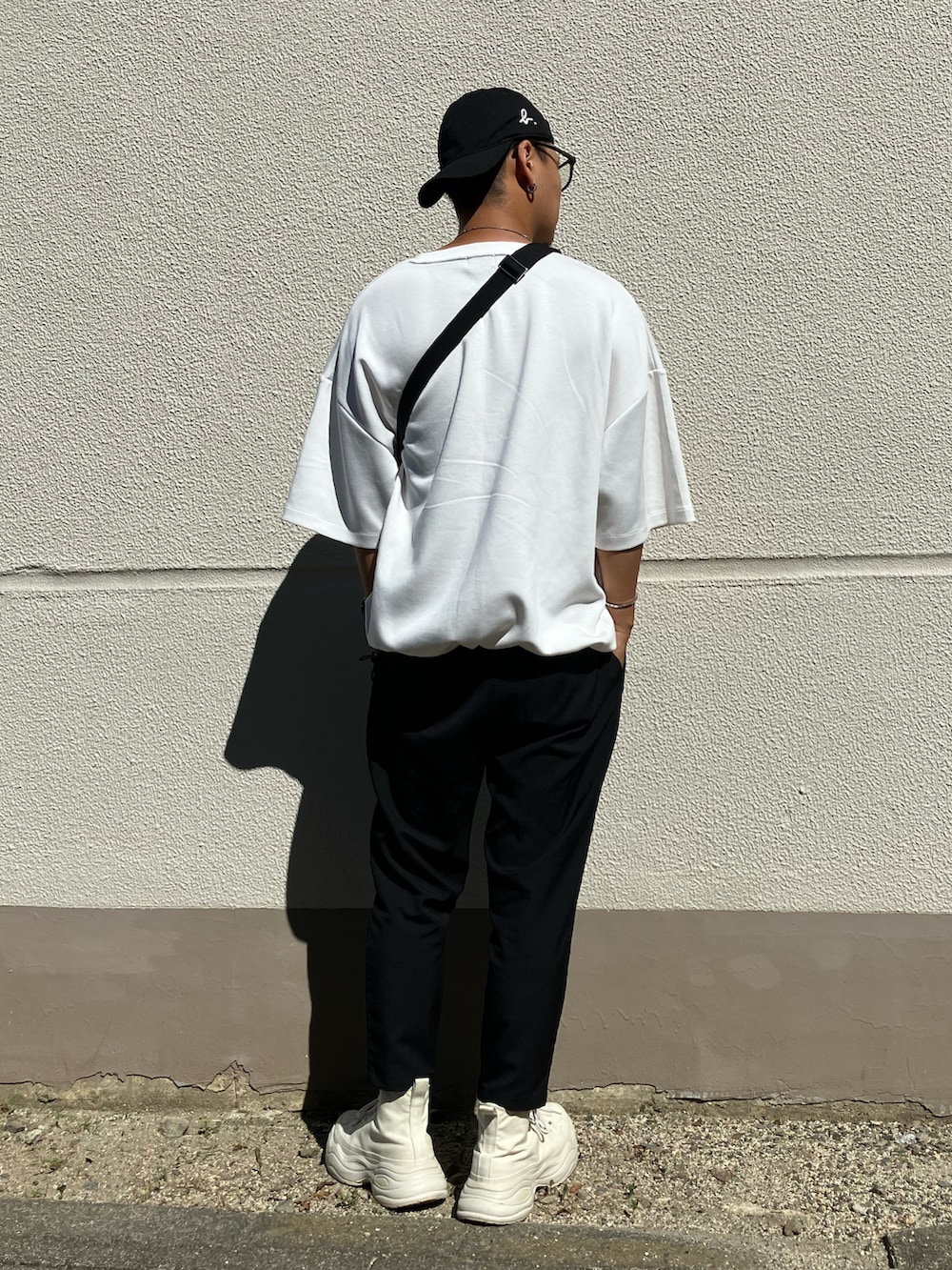 ホワイト系のスニーカー、ホワイト系のTシャツ/カットソー、ブラック系のメッセンジャーバッグを着用したメンズの秋コーディネートの2枚目の写真