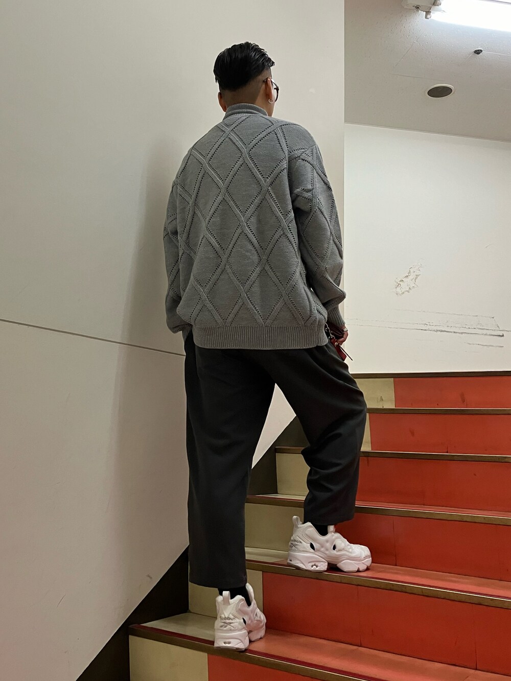 グレー系のニット/セーター、グレー系のパンツ、ホワイト系のスニーカーを着用したメンズの秋コーディネートの2枚目の写真