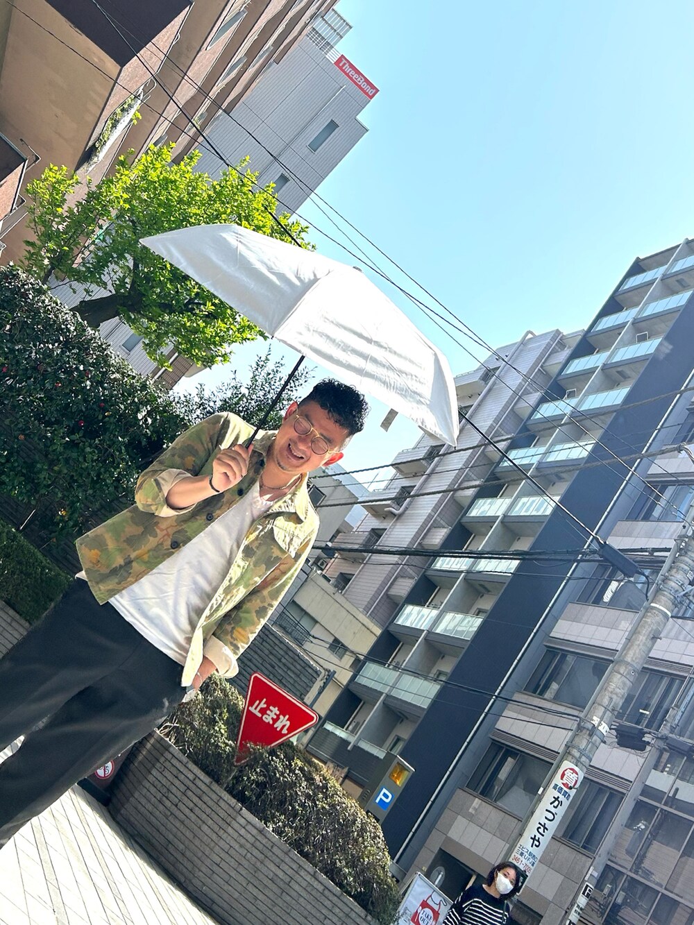 ブラック系のサンダル、グレー系のスラックス、ホワイト系の折りたたみ傘を着用したメンズの春コーディネートの3枚目の写真