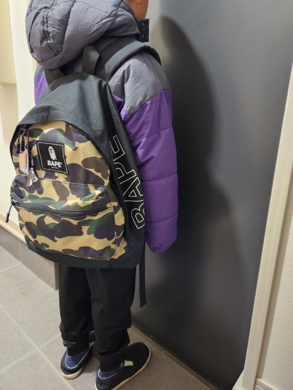 パープル系のダウンジャケット/コート、ブラック系のスリッポンを着用したキッズの冬コーディネートの2枚目の写真