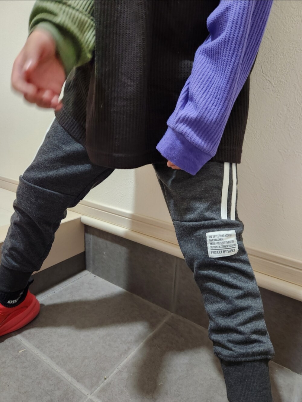 グレー系のスウェットパンツ、ブラック系のTシャツ/カットソー、レッド系のスニーカーを着用したキッズの秋コーディネートの4枚目の写真