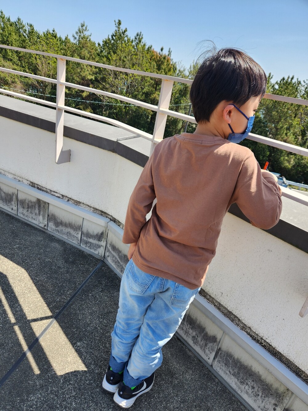 ブラウン系のTシャツ/カットソー、ブルー系のデニムパンツ、ブラック系のスニーカーを着用したキッズの春コーディネートの2枚目の写真