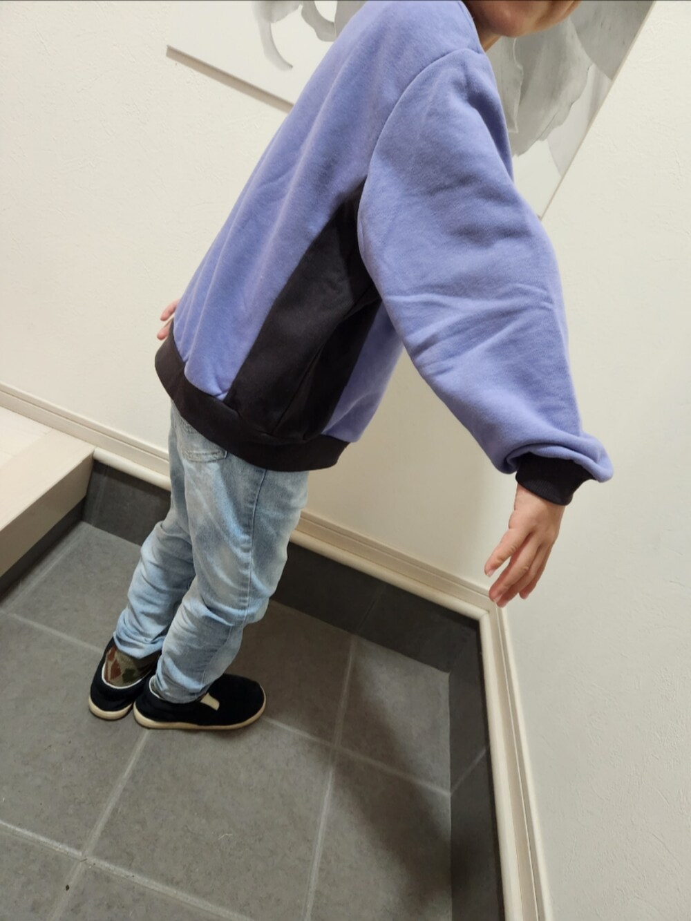 パープル系のスウェット、ブルー系のデニムパンツ、ブラック系のスリッポンを着用したキッズの冬コーディネートの3枚目の写真