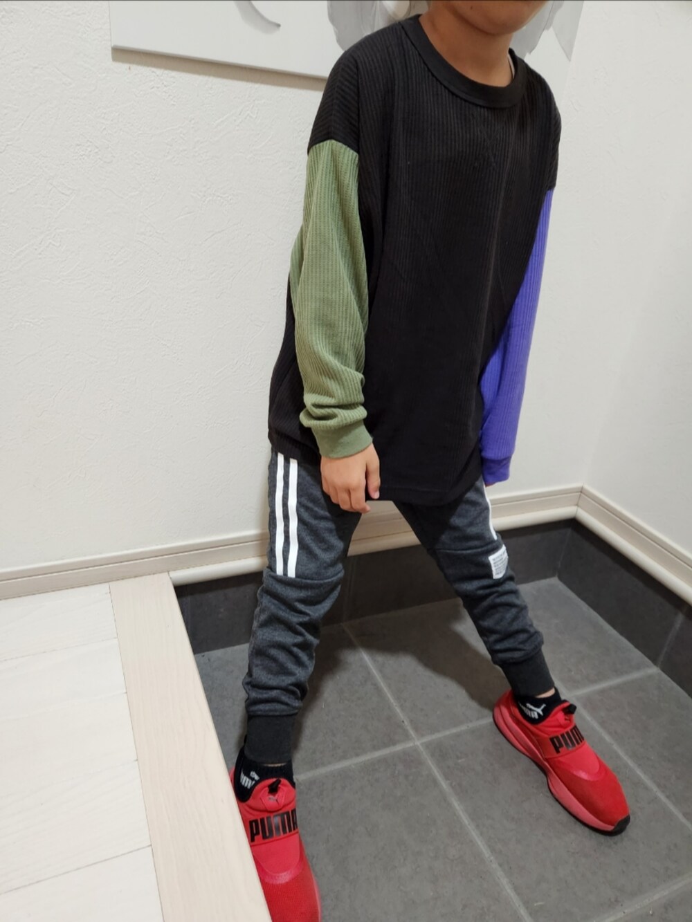 グレー系のスウェットパンツ、ブラック系のTシャツ/カットソー、レッド系のスニーカーを着用したキッズの秋コーディネートの2枚目の写真