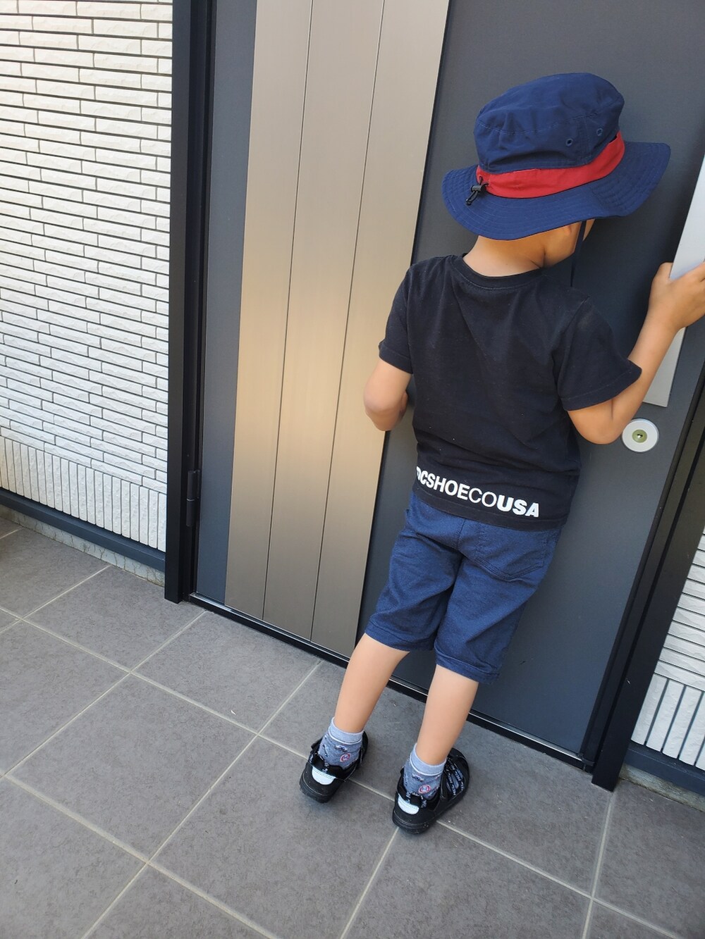 ブラック系のTシャツ/カットソー、ブラック系のサンダル、ブルー系のパンツを着用したキッズの春コーディネートの2枚目の写真