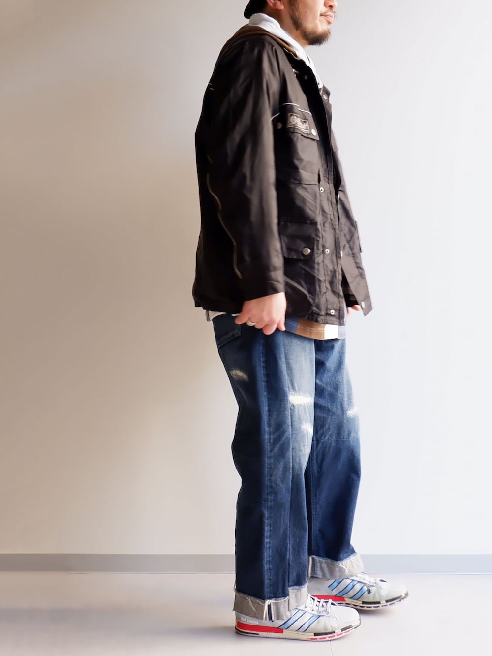 ブルー系のデニムパンツ、ブラック系のノーカラージャケット、ホワイト系のスニーカーを着用したメンズの冬コーディネートの2枚目の写真