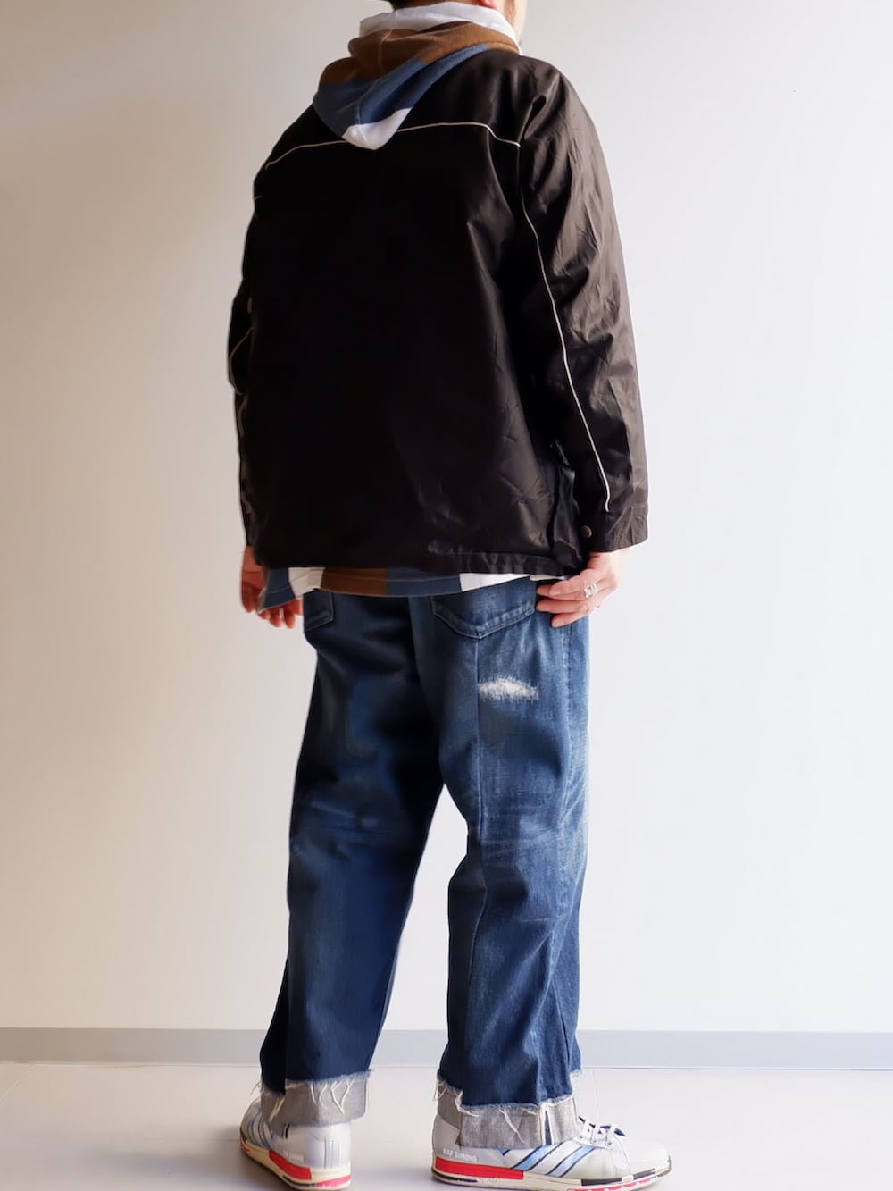 ブルー系のデニムパンツ、ブラック系のノーカラージャケット、ホワイト系のスニーカーを着用したメンズの冬コーディネートの3枚目の写真