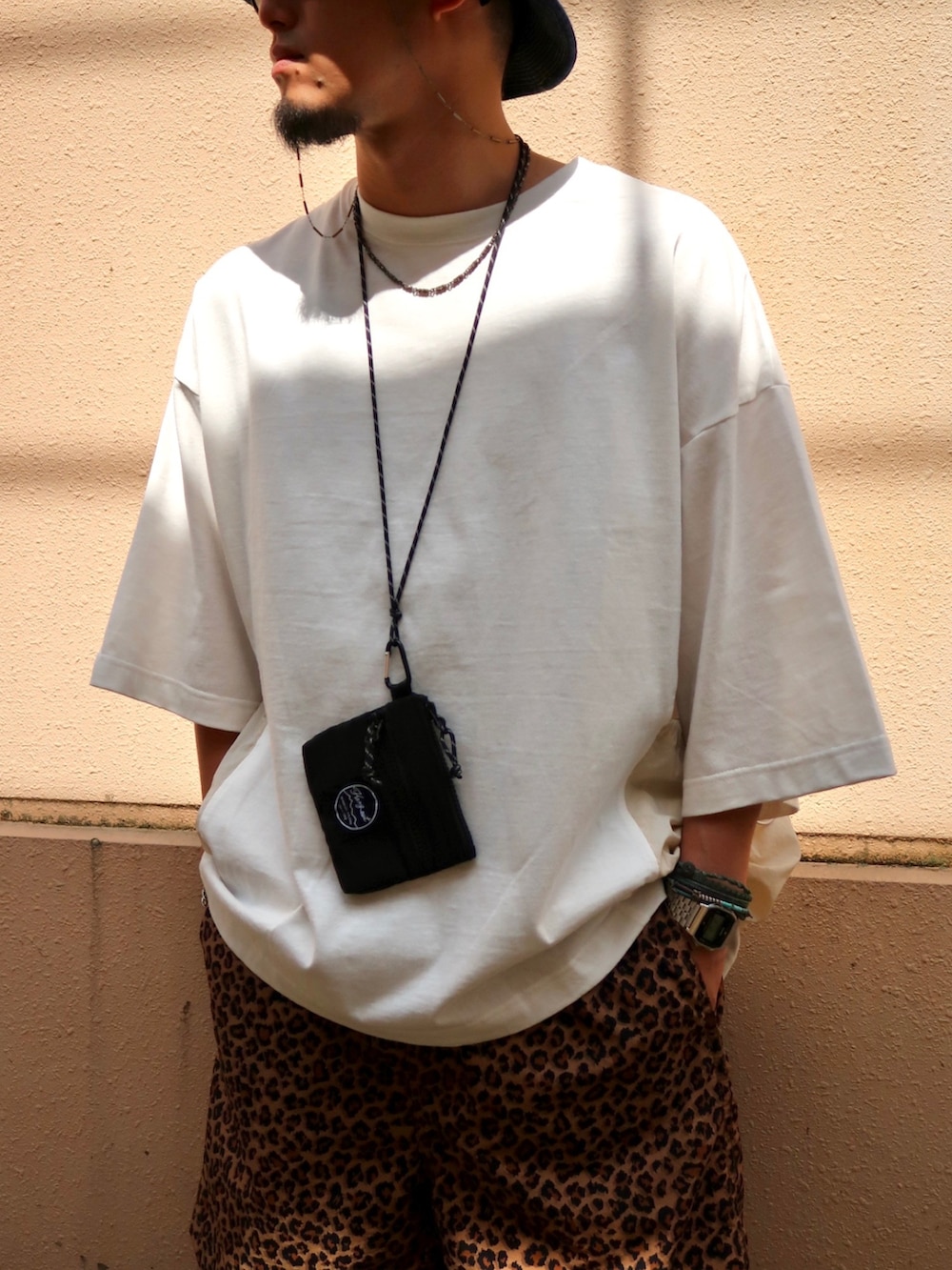 ホワイト系のTシャツ/カットソー、ブラック系のショルダーバッグ、ブラック系のサンダルを着用したメンズの夏コーディネートの3枚目の写真