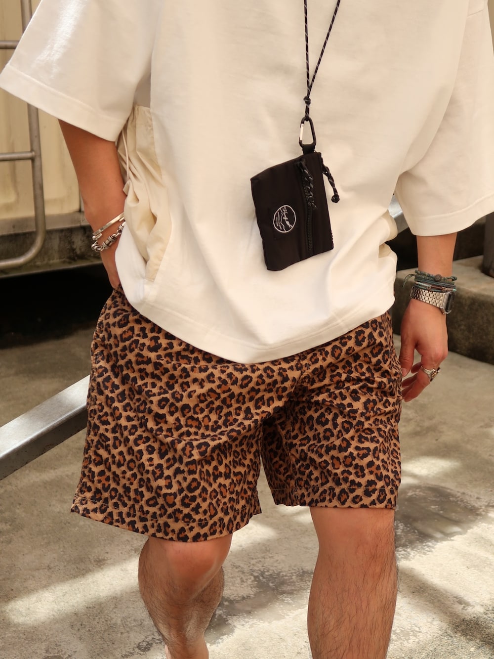 ホワイト系のTシャツ/カットソー、ブラック系のショルダーバッグ、ブラック系のサンダルを着用したメンズの夏コーディネートの4枚目の写真