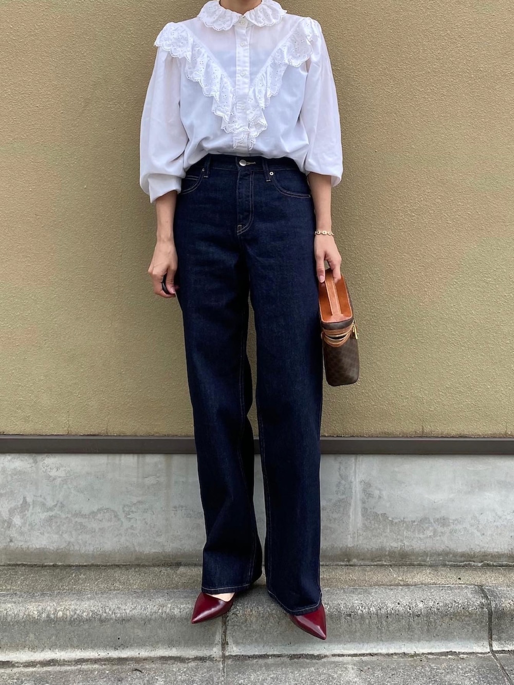 ブルー系のデニムパンツ、ブラウン系のバッグ、レッド系のパンプスを着用したレディースの夏コーディネートの2枚目の写真