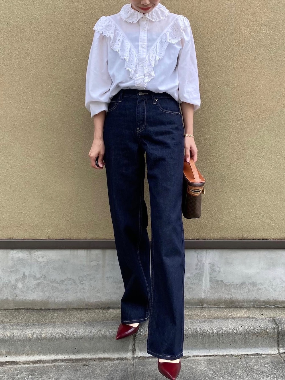 ブルー系のデニムパンツ、ブラウン系のバッグ、レッド系のパンプスを着用したレディースの夏コーディネートの3枚目の写真