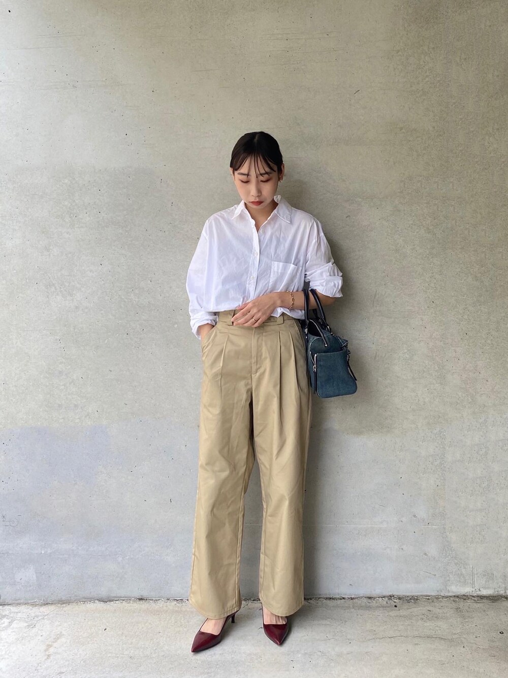 ホワイト系のシャツ/ブラウス、ブルー系のボストンバッグ、ベージュ系のチノパンツを着用したレディースの夏コーディネートの3枚目の写真