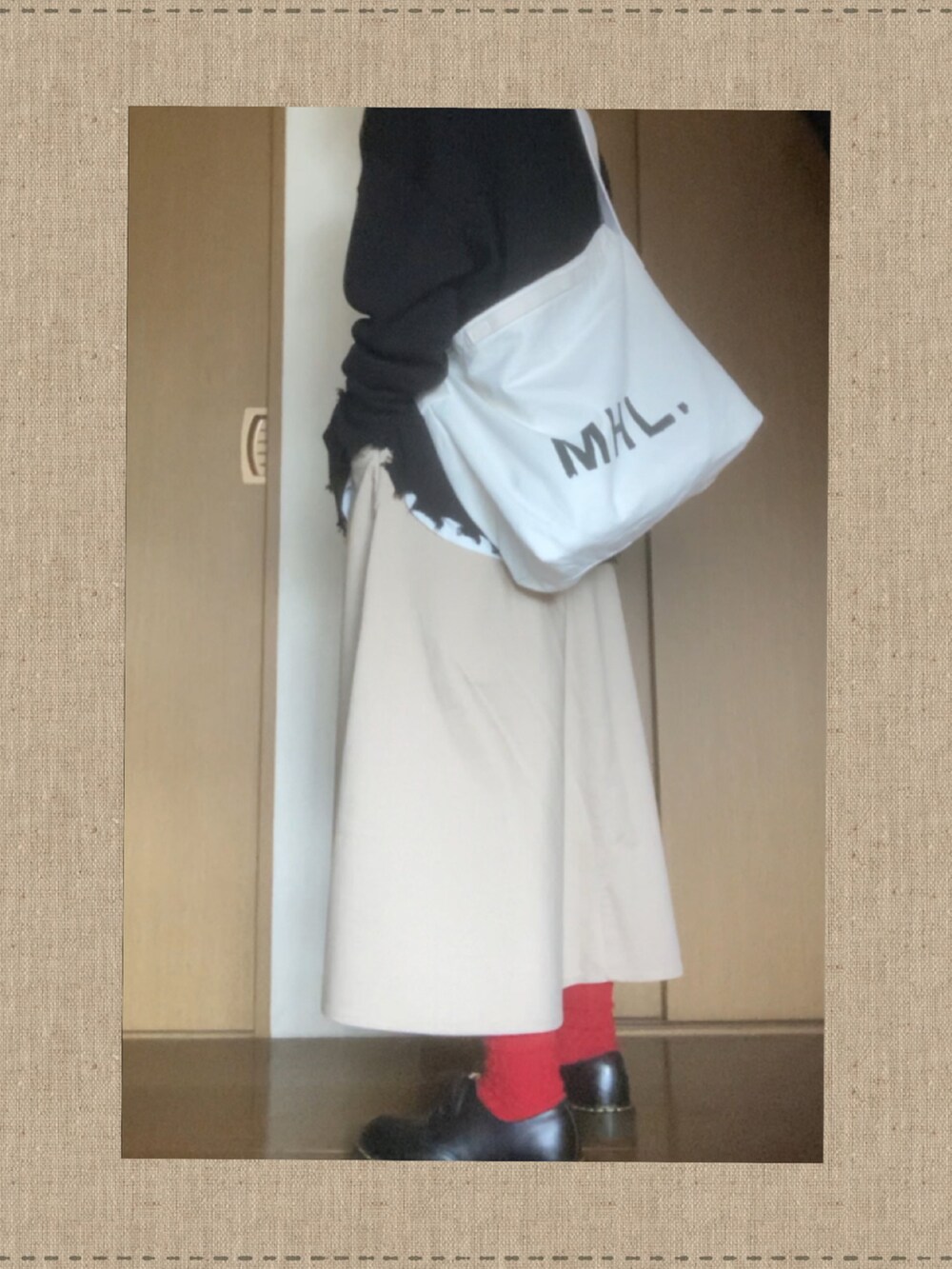 ブラック系のニット/セーター、ホワイト系のTシャツ/カットソー、ホワイト系のショルダーバッグを着用したレディースの春コーディネートの2枚目の写真