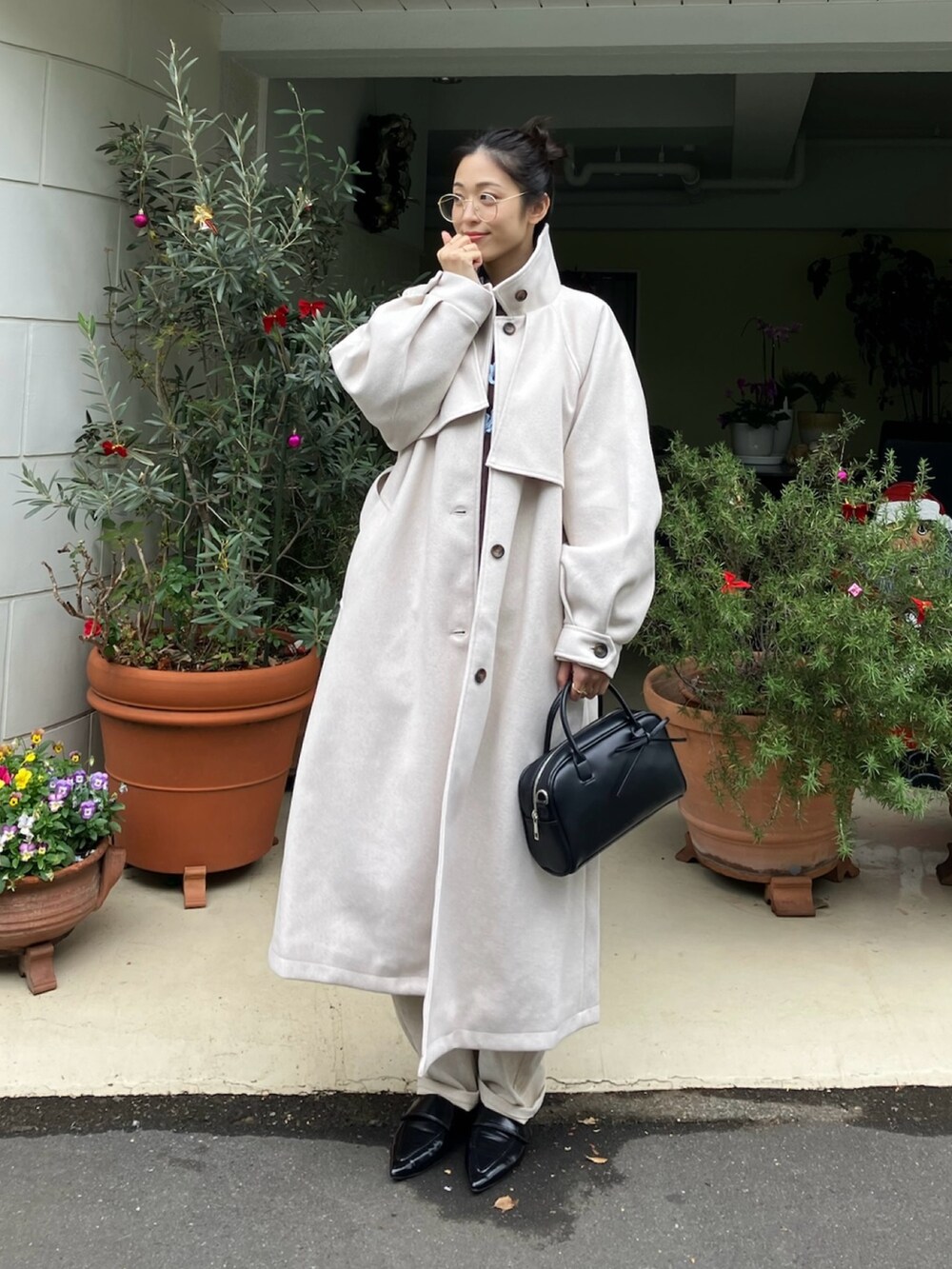 ベージュ系のステンカラーコート、ブラック系のシャツ/ブラウス、ブラウン系のニット/セーターを着用したレディースの秋コーディネートの2枚目の写真