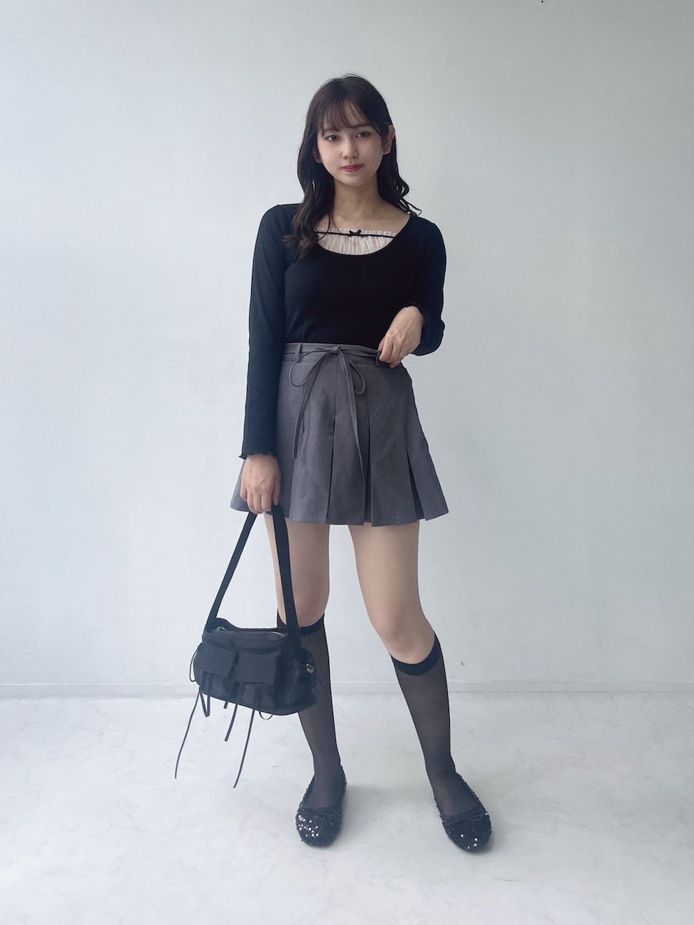 グレー系のスカート、ブラック系のパンプス、ブラック系のショルダーバッグを着用したレディースの夏コーディネートの2枚目の写真