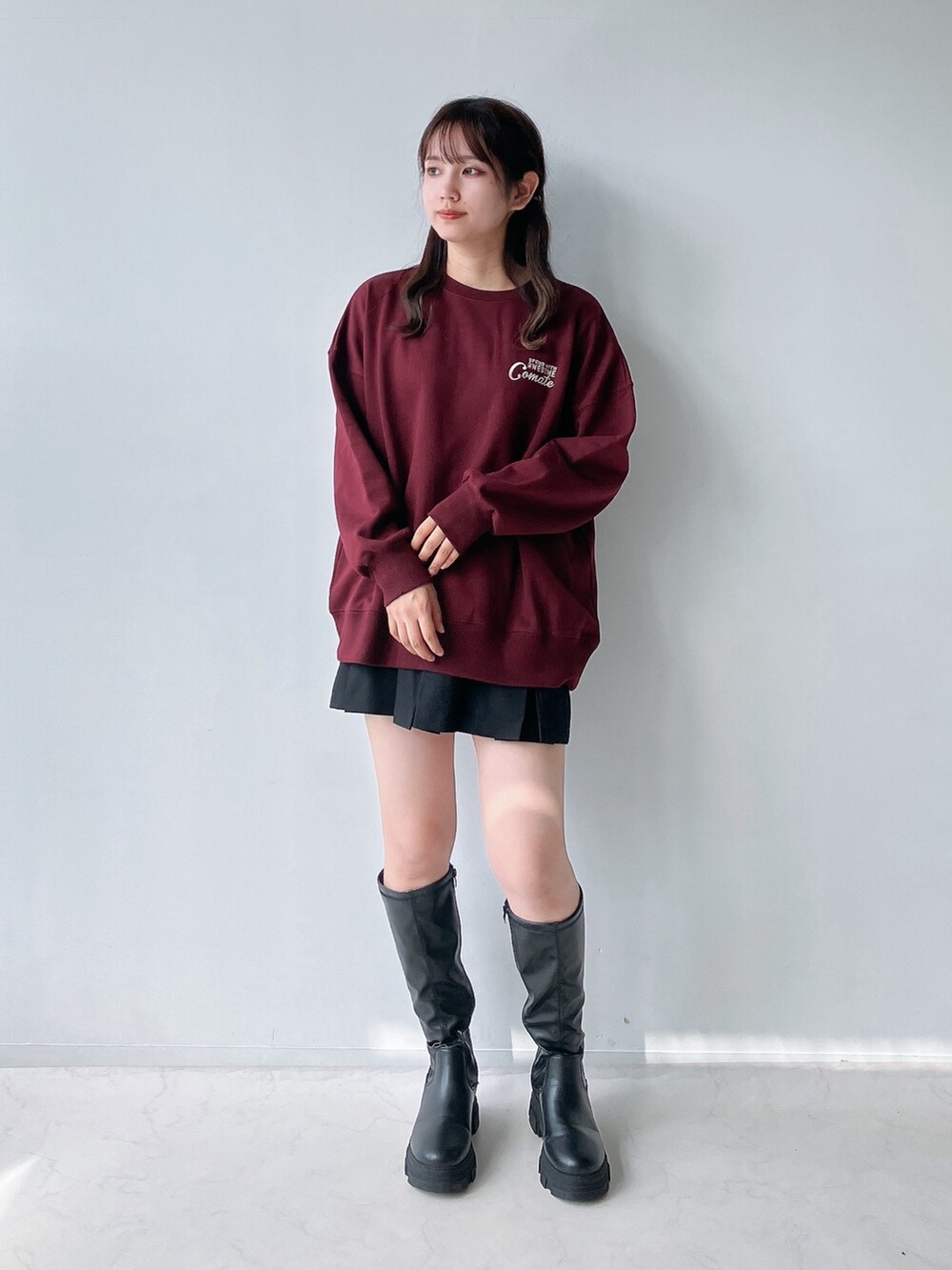 ブラック系のブーツ、ブラック系のスカート、レッド系のスウェットを着用したレディースの秋コーディネートの2枚目の写真