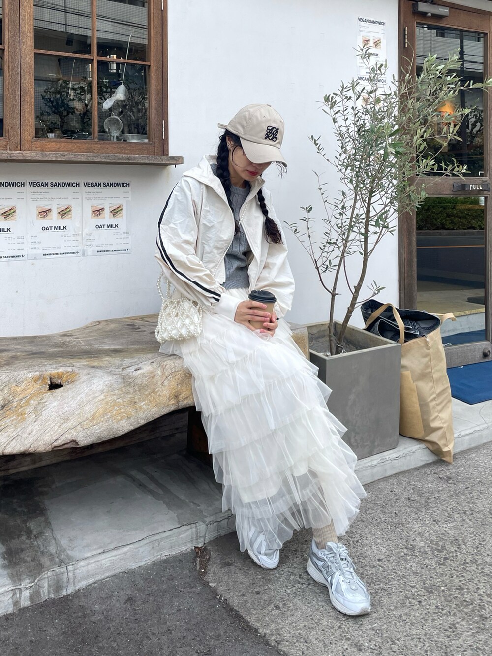 ホワイト系のショルダーバッグ、グレー系のニット/セーター、ホワイト系のスカートを着用したレディースの春コーディネートの2枚目の写真