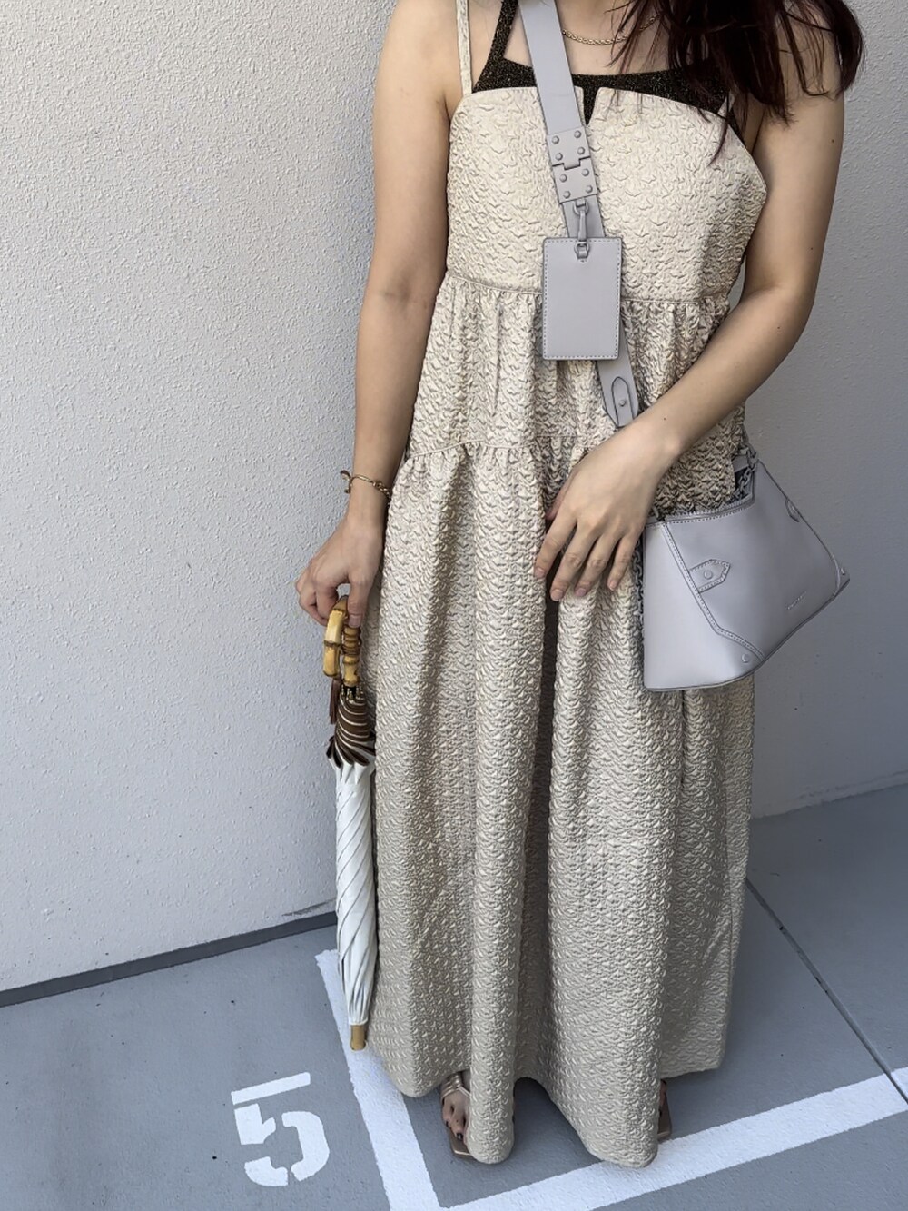 ベージュ系のワンピース、ベージュ系のサンダル、ブラウン系のキャミソールを着用したレディースの秋コーディネートの2枚目の写真