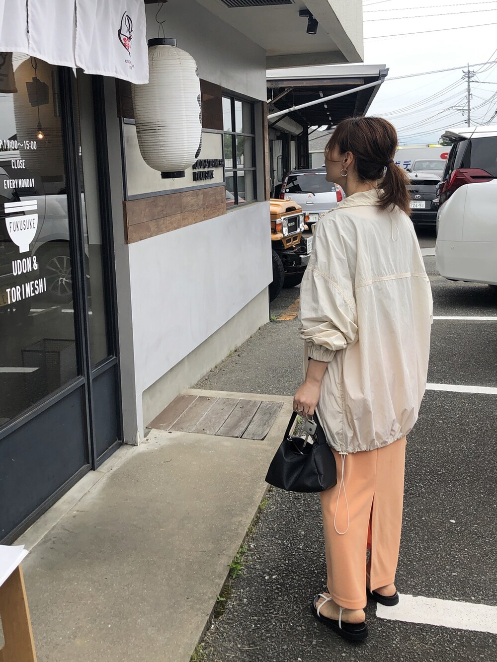 ブラック系のTシャツ/カットソー、オレンジ系のスカート、ホワイト系のサンダルを着用したレディースの夏コーディネートの5枚目の写真