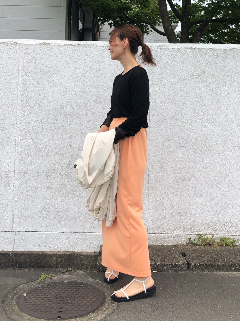 ブラック系のTシャツ/カットソー、オレンジ系のスカート、ホワイト系のサンダルを着用したレディースの夏コーディネートの4枚目の写真